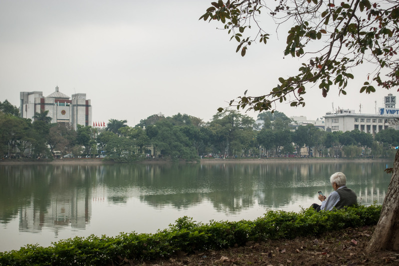 old man on his phone by the lake