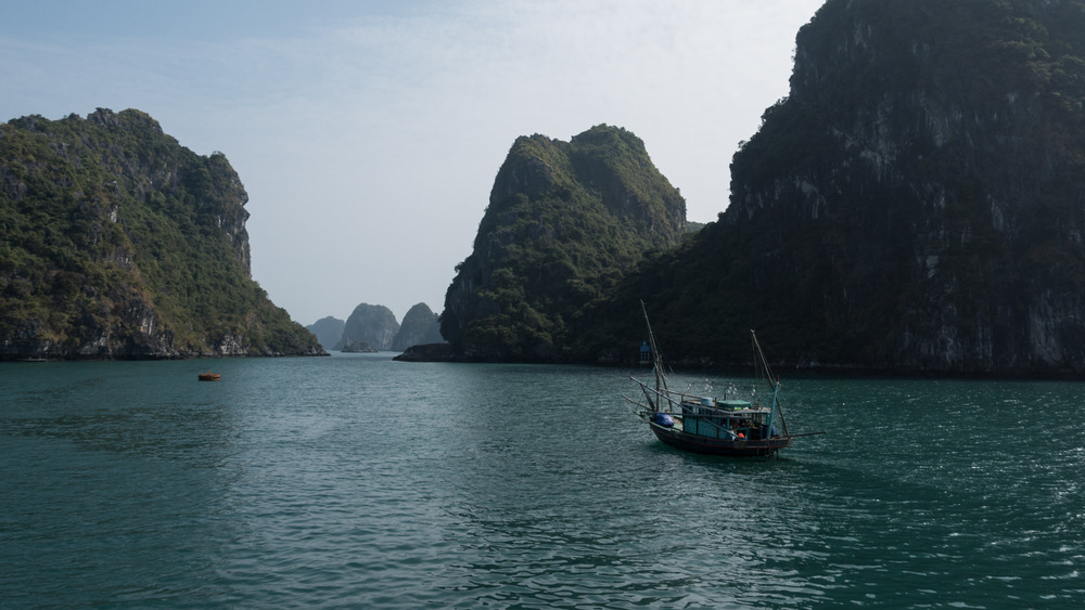 fishing boat in front of rocky islands