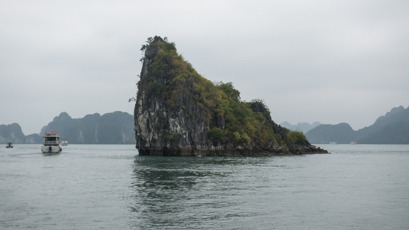 triangular rock island next to boats