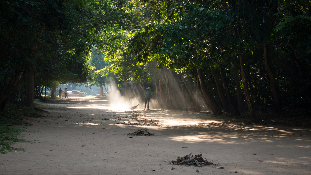 woman sweeping the dirt road