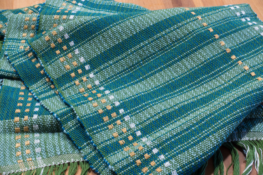 blue-green striped scarf, folded on a table