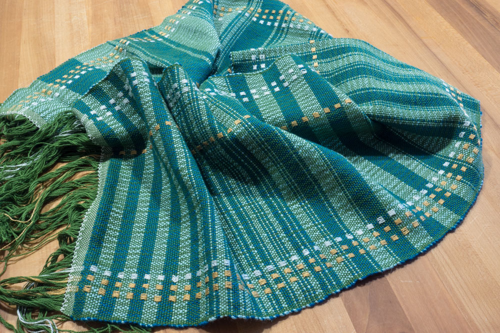 blue-green striped scarf, coiled in a circle on a table