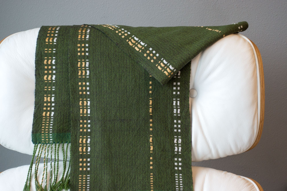 dark green, gold, and white scarf draped over a chair