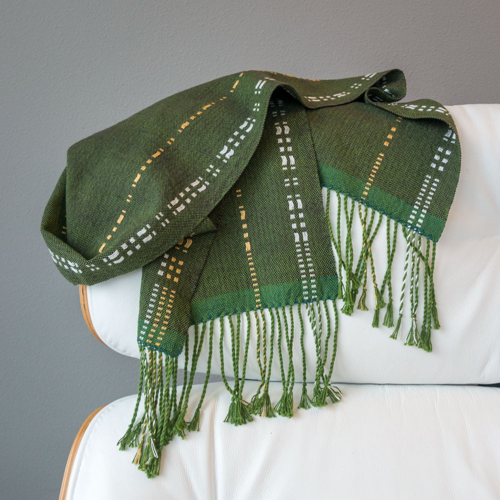 dark green, gold, and white scarf lying crumpled on a chair