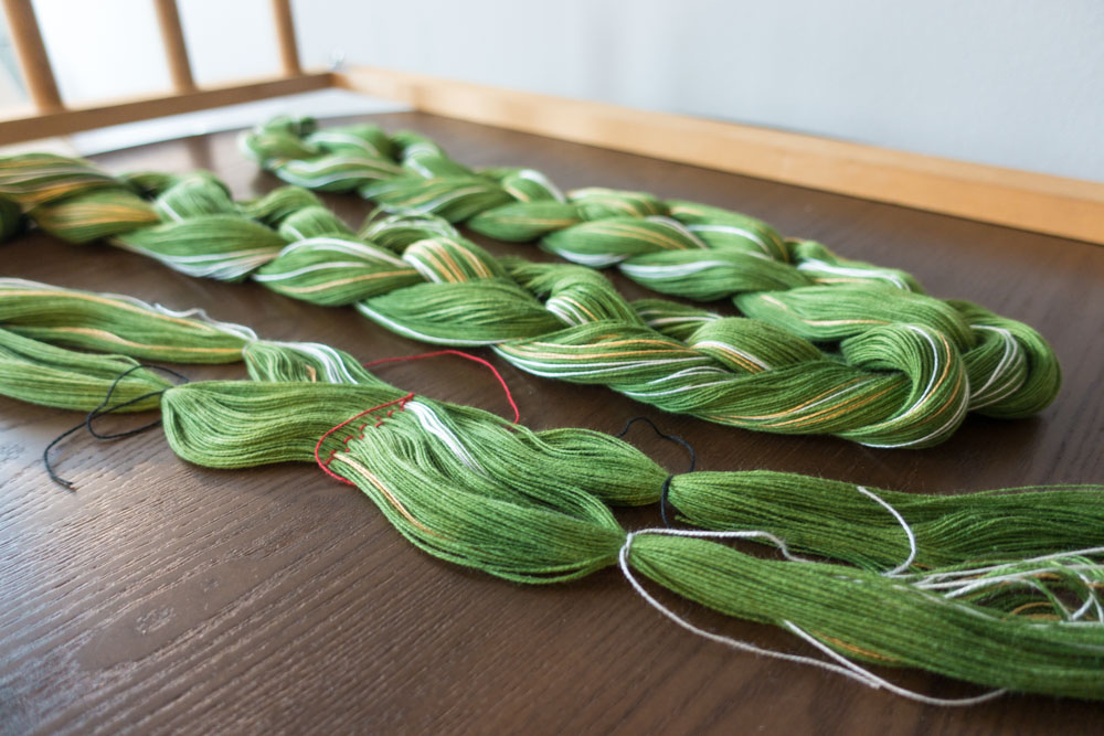 crochet-chained green warp threads lying on a table
