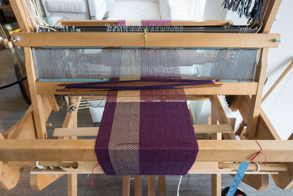 purple scarf being woven on a loom