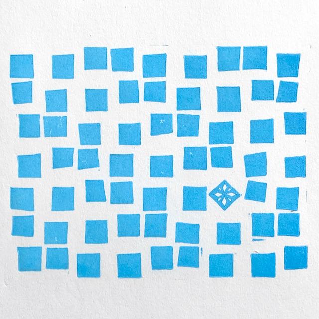 A haphazard array of light blue squares printed on white paper. One of the squares is rotated 45 degrees and has a star pattern carved inside.