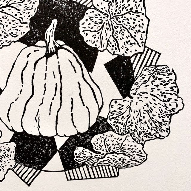 A closeup view of a black and white print depicting an overgrown pumpkin surrounded by pumpkin leaves and geometric designs.