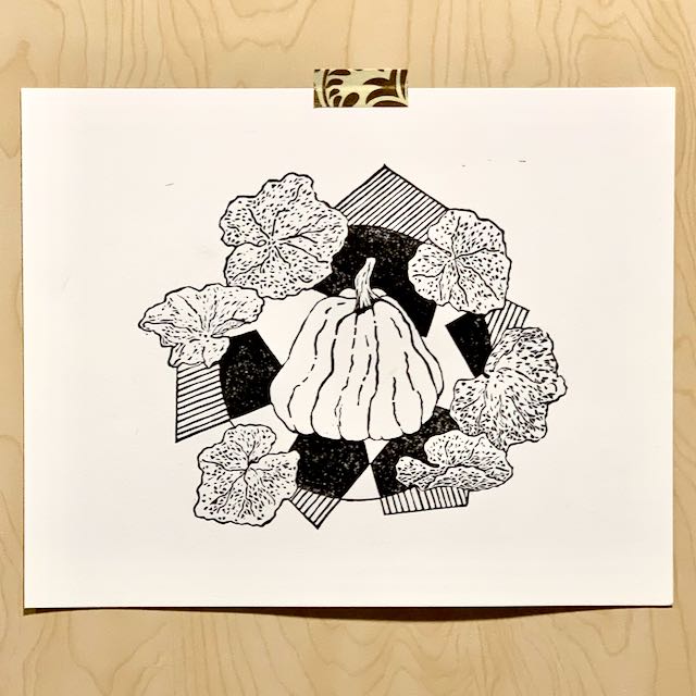 A print of a large overgrown pumpkin surrounded by pumpkin leaves and geometric designs. The print is black ink on cream paper, and is taped to a wooden backdrop.