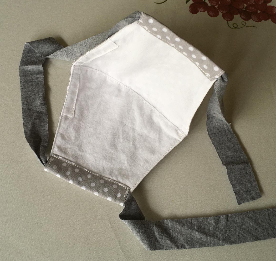 The interior of the fabric face mask is white, with a sewn pocket at the top to hold a bendable nose wire.