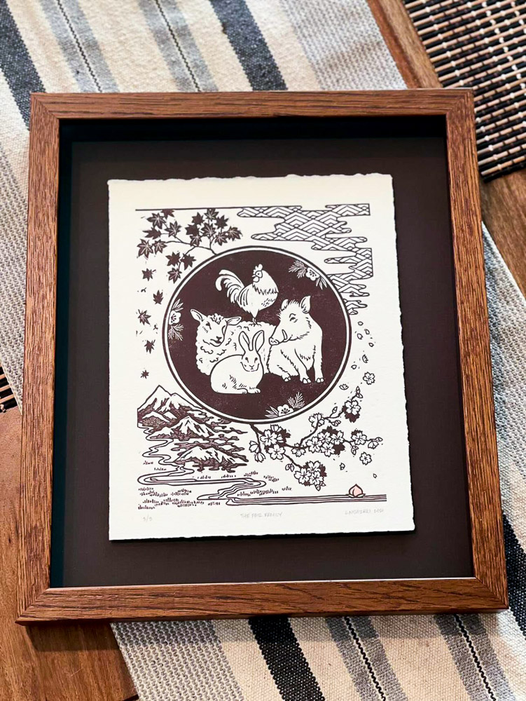 A customer image showing the print float-framed above a black matboard, within a dark wood frame. The frame sits on a striped table-runner.