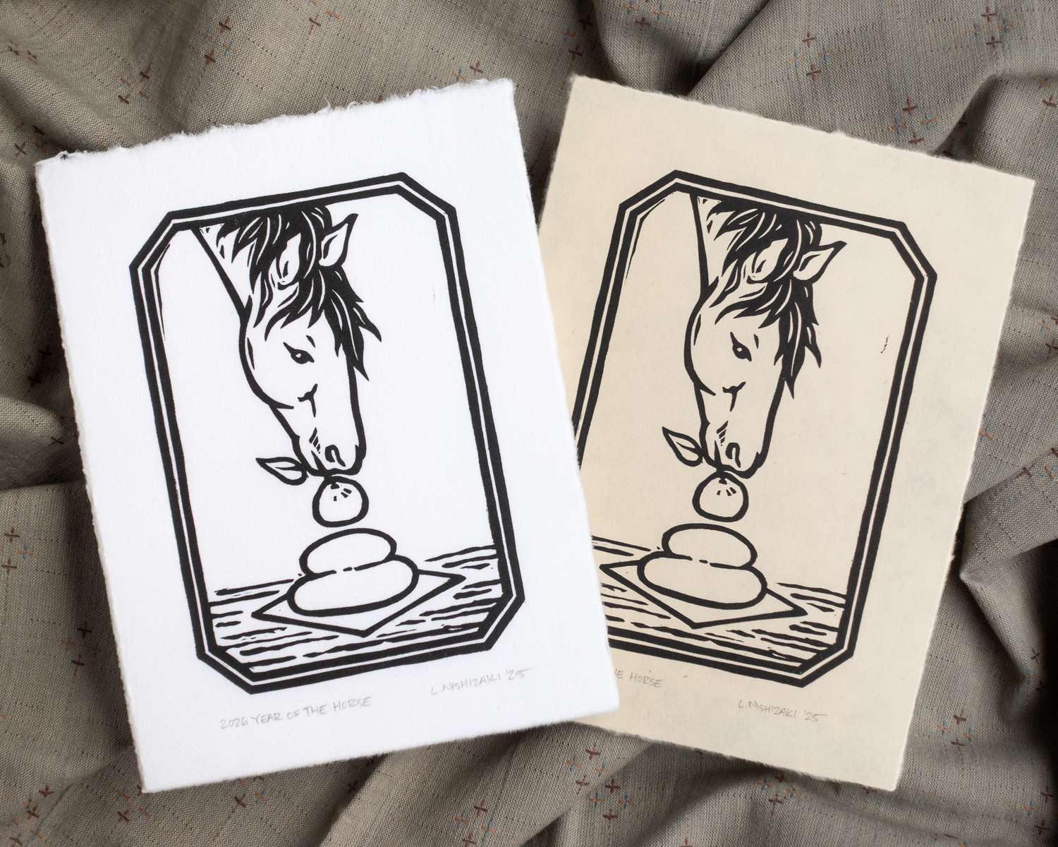 Two blockprints showing a horse grabbing a mandarin orange from the top of a kagami mochi. One blockprint is on white paper; the other is on a pale tan paper.