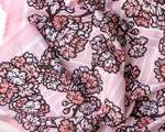 A rumpled fabric depicting an all-over pattern of pink cherry blossoms on branches