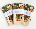 Three rectangular folded kitchen towels, all with the same orange persimmon pattern and white packaging band