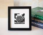 A framed black-and-white print of Mt. Index, next to a stack of mountaineering books.