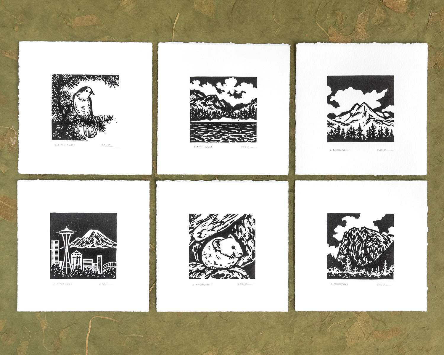 A 2x3 grid of 6 square prints on a green backdrop; each has black and white illustrations of mountains and critters