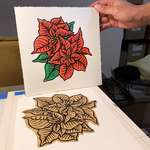 A hand holds up the finished poinsettia blockprint. The linoleum block showing black linework is directly below.