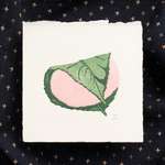 A pink and green print of a Japanese mochi dessert, printed using simple block shapes on thick cream colored paper. The print is labelled on the bottom right edge with the artist initials LN and the edition number 1/100. The paper has rough textured edges (the top edge of the print is a deckle edge). The print lies on top of a geometric navy piece of fabric.