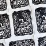 Many black and white illustrations of snakes, slightly overlapping on a flat surface.