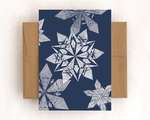 A single card with a brown envelope. The card depicts a five white impressions of origami snowflakes on a navy background.